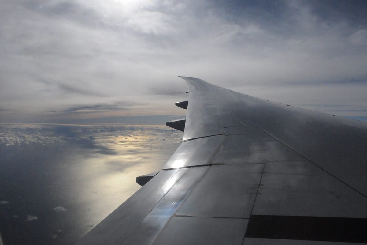 Vista desde la ventanilla del ala de un avión sobre el mar al atardecer